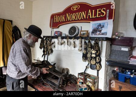 Drayman, Roger Hughes checks the horses harness in the stable tack room before the beer deliveries at the family owned Hooks Norton Brewery founded in Stock Photo