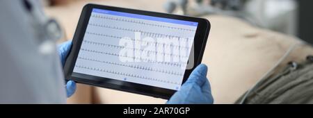 Female doctor hold in hand tablet pc with patient electrocardiogram Stock Photo