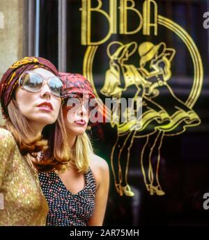 London 1970s, two elegant women portrait with sunglasses, Biba department store sign, Kensington High street, England, UK, GB, Great Britain, Stock Photo