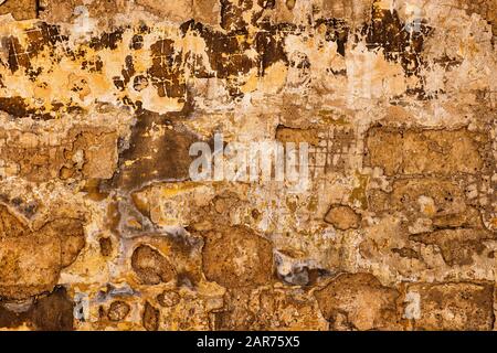Old grunge wall texture and background, weathered stone blocks behind layers of plaster and paint, taken in medieval city of Mdina in Malta, Europe. Stock Photo