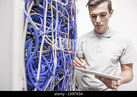 Man using tablet pc beside servers in data center internet technology concept Stock Photo