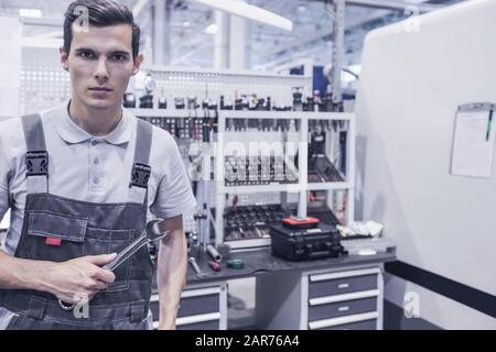 Mechanical technician worker at cnc milling plant workshop holding wrench Stock Photo