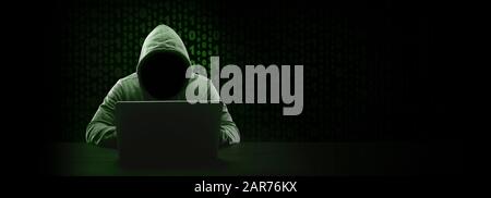 hacker without face in a hood over binary code background, panoramic mock-up with space for text Stock Photo
