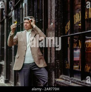 London 1970s, man examines a sherry wine glass outside Berry Bros. & Rudd wine merchants store, St James street, England, UK, GB, Great Britain, Stock Photo