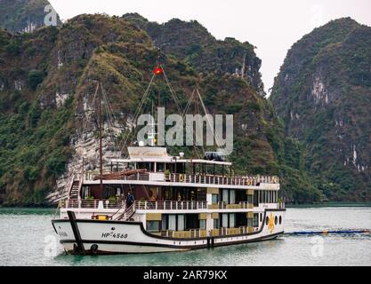 Orchid tourist cruise ship with kayaks & limestone karst rock cliffs, Halong Bay, Vietnam, Asia Stock Photo