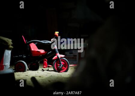 an abandoned children's bike dusting in the attic among the old trash. The concept of forgotten childhood. Copy space Stock Photo