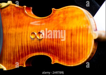 wedding rings lie on the back deck of the violin. top view Stock Photo