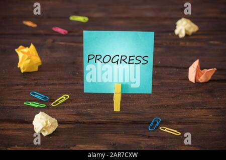 card attached to the clip with the hand-written inscription "Progress" Wooden background. The concept of development and achieving set goals Stock Photo