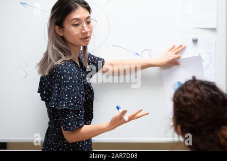 Focused asian female speaker make presentation on board Stock Photo