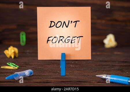 card attached to the clip with the hand-written inscription "Don't Forget" Wooden background. Office and business concept Stock Photo