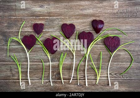 Flowers of sliced boiled beets and green onions on a wooden background. To love beets. Healthy eating concept. Stock Photo