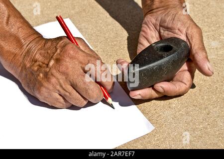 An old stone Hammer an elder man holds in his hands. Archaeology. Study of ancient objects Stock Photo