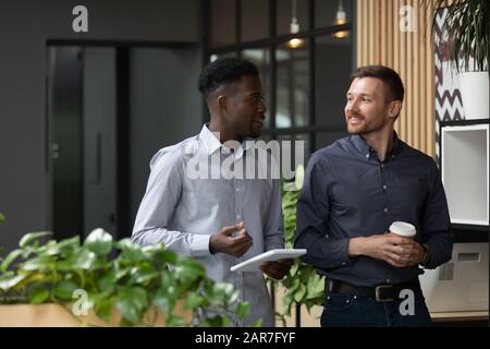 Multiethnic male colleagues stand talking discussing ideas Stock Photo