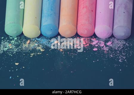 Crumbs and chunks of multicolored chalk, pastels on the school board. Yellow, pink, red, green, gray, light green crimson Stock Photo