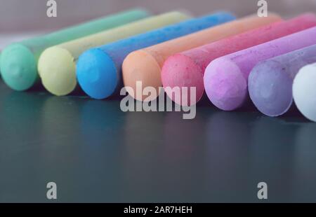 Chunks of multicolored chalk, pastels on the school board. Yellow, pink, red, green, gray, light green crimson Stock Photo