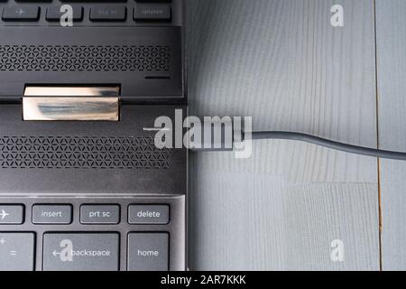 USB Type C grey cable connected to the laptop computer. Flat lay top view. Stock Photo