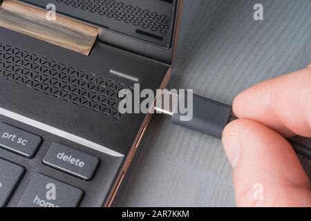 Closeup of USB Type C grey cable being connected to the laptop computer. Stock Photo