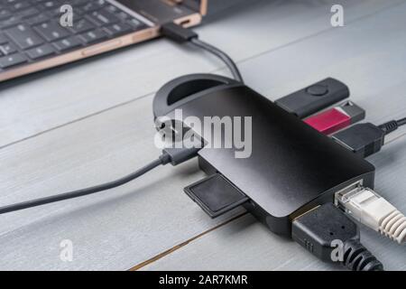 USB Type C adapter or hub connected to the laptop with various accessories - pendrives, hdmi, ethernet, memory card, cables. Stock Photo