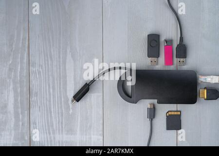 USB Type C adapter or hub with various accessories - pendrives, hdmi, ethernet, memory card, cables. Flat lay top view. Large copy space on the left. Stock Photo