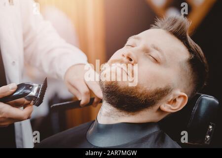 Hipster client man visiting in barber shop shaving beard Stock Photo