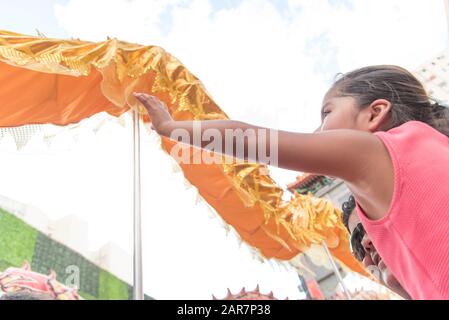 Capital Federal, Buenos Aires / Argentina; Jan 25, 2020: Little girl trying to touch a golden dragon in the celebrations of the Chinese new year, luna Stock Photo