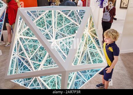 Miami Florida,Art Basel,Art Miami,inside interior,gallery,exhibit,Anthony James,neon sculpture,boy,child,looking,infinity mirror mirrors,FL191231069 Stock Photo