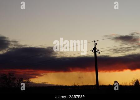 Silhouette high voltage electric tower on sunset sky background. Stock Photo