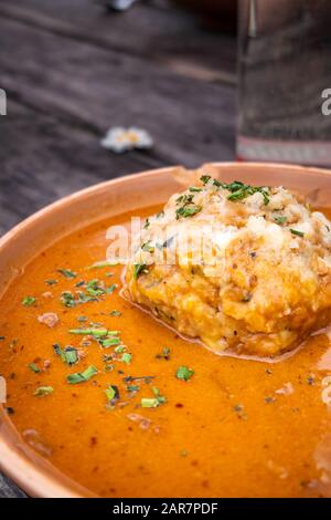 Tasty mushroom goulash with bread dumpling and some parsley and chives on top on a rustic wooden table on a mountain hut in Carinthia, Austria Stock Photo