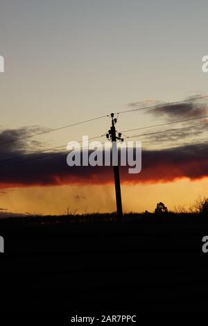 Silhouette high voltage electric tower in sunset sky. Stock Photo
