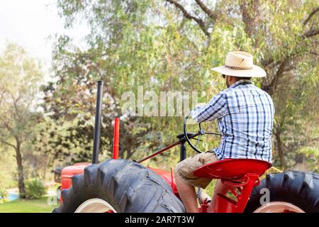 Handsome man with sunglasses driving the tractor to work on the farm Stock Photo