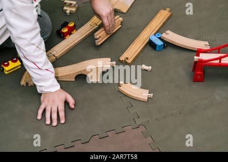 The boy collects a wooden constructor. Toy railway with a train made of wood. Educational toys Stock Photo
