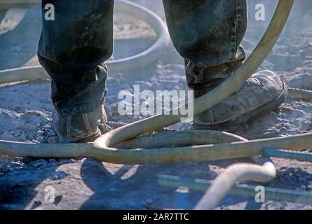 Construction worker's boots while using a jackhammer Stock Photo