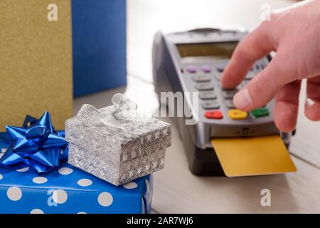 Holiday gifts in the foreground. Customer entering a PIN code Stock Photo