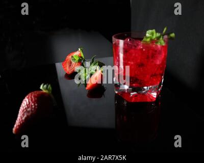 Fresh red cocktail with ice cubes and mint leaves. Red summer berries . Tasty juicy drink. Stock Photo