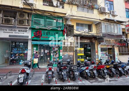 Motorbikes parked in front of old shops. Macau, China. Stock Photo