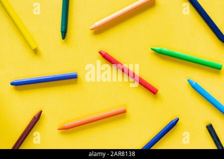 Yellow minimalistic background with colorful wax pastel crayon pencils Stock Photo