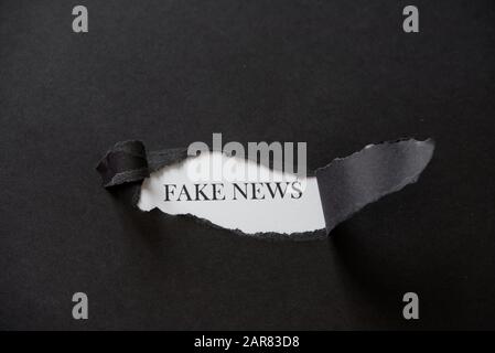 Fake news printed on a white background with black torn paper. Fake Stock Photo