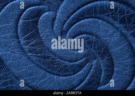 Texture of dark blue genuine leather close-up, with embossed twirl curve, spiral, trend pattern. Fashionable background, for banner design Stock Photo