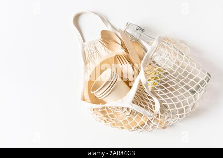 Cotton mesh bag for shopping with disposable tableware. Zero waste, plastic free, sustainable lifestyle concept. Flat lay. Copy space. Stock Photo