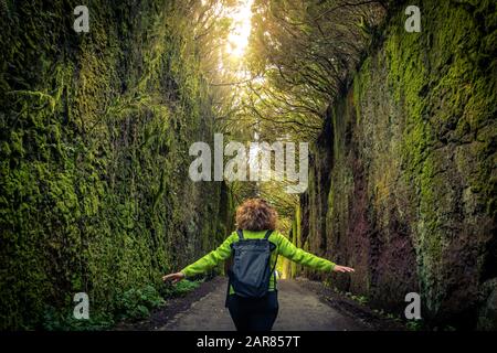 Woman walks alone in a beautiful natural setting of the Anaga Park, Tenerife Canary Islands Spain. Girl tourist walking on the path between two rock w Stock Photo