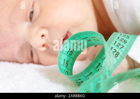 Little baby infant boy head with green centimeter on foreground Stock Photo