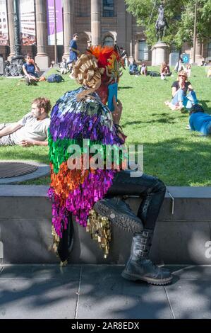Colourfully-costumed artiste makes a call outside the State Library of Victoria on Swanston Street, Melbourne, Australia Stock Photo