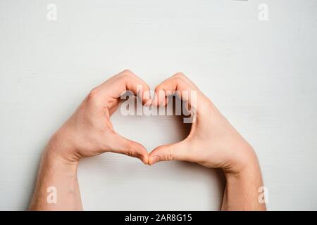 Abstract heart made of hands on a white wooden background. top view. Stock Photo
