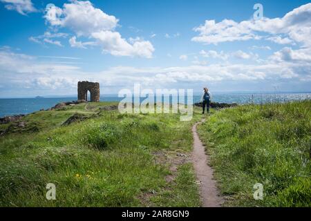 Tourist on the hiking path leading to the unusual stone Lady Tower built in the 1760's perched on the North Sea, East Neuk of Fife, Elie, Scotland, UK Stock Photo