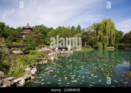 Tower of Condensing Clouds pavilion and the Dream Lake with a Salix - Weeping Willow tree in Chinese Garden in late spring, Montreal Botanical Garden Stock Photo