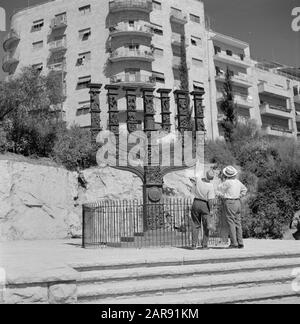 Israel 1964-1965: Jerusalem (Jerusalem), street images  Two passers-by looking and pointing at a menora on the street 5 meters high (seen from the opposite Knesset (parliament building) Annotation: A menora is a seven-armed candlestick and the ancient symbol for the Hebrew people (also it is one of the oldest symbols for Judaism in general) Date: 1964 Location: Israel, Jerusalem Keywords: visitors, apartment buildings, candlestick, street sculptures, pedestrians Stock Photo