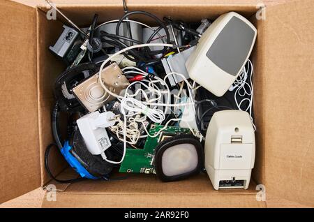 Modern electronic waste in a cardboard box. HDD, power supply, speaker, cable, headphone, antenna, computer parts, circuit board Stock Photo