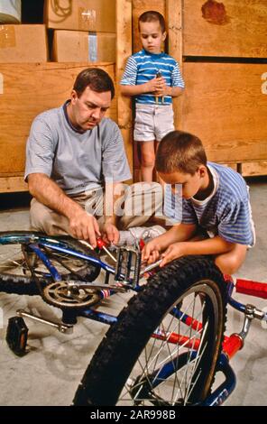 In their suburban garage in Laguna Niguel, CA, a father helps his two sons repair their bicycles. MODEL RELEASE Stock Photo