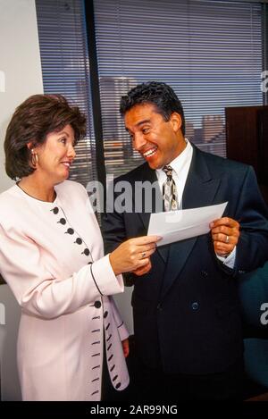 A woman office manager gets a bonus paycheck from her male boss in Irvine, CA. Stock Photo