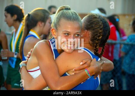 A high school track and field foot race winner is hugged by a team mate at the finish line of a school track meet in Laguna Hills, CA. Stock Photo